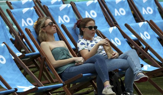 Spectators wait for play to start in Garden Square ahead of the first round singles matches at the Australian Open tennis championship in Melbourne, Australia, Monday, Jan. 20, 2020. (AP Photo/Dita Alangkara)