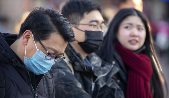 Travelers wear face masks as they walk outside of the Beijing Railway Station in Beijing, Monday, Jan. 20, 2020. China reported Monday a sharp rise in the number of people infected with a new coronavirus, including the first cases in the capital. The outbreak coincides with the country&#39;s busiest travel period, as millions board trains and planes for the Lunar New Year holidays. (AP Photo/Mark Schiefelbein)