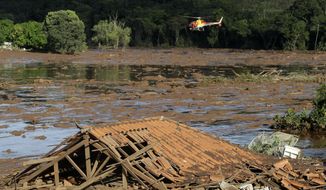 FILE - In this Sunday, Jan. 27, 2019 file photo, rescue workers in a helicopter search a flooded area after a dam collapsed in Brumadinho, Brazil. Prosecutors in the Brazilian state of Minas Gerais said Tuesday, Jan. 21, 2020 they will present charges against mining giant Vale, its German auditor Tuv Sud and 16 individuals in connection with the dam collapse last January that killed more than 200 people. (AP Photo/Andre Penner, File)