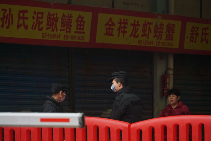 Police stand guard outside Wuhan Huanan Wholesale Seafood Market, where a number of people related to the market fell ill with a virus in Wuhan, China, Tuesday, Jan. 21, 2020. Heightened precautions were being taken in China and elsewhere Tuesday as governments strove to control the outbreak of the coronavirus, which threatens to grow during the Lunar New Year travel rush. (AP Photo/Dake Kang)
