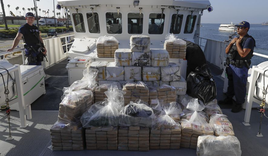 In this Aug. 29, 2019, file photo, members of the Coast Guard stand near seized cocaine in Los Angeles. (AP Photo/Chris Carlson, file)