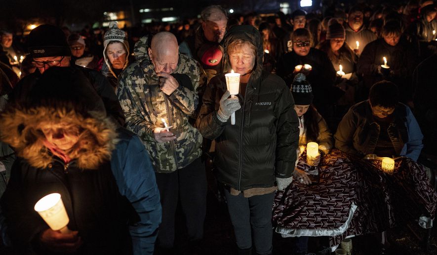 Jack and Holly Nelson, center, join others in prayer during a candlelight vigil for the Haynie family at City Park in Grantsville, Utah, Monday, Jan. 20, 2020. Police say four members of the Haynie family were killed and one injured after being shot by a teenage family member on Jan. 17. (Spenser Heaps/The Deseret News via AP)