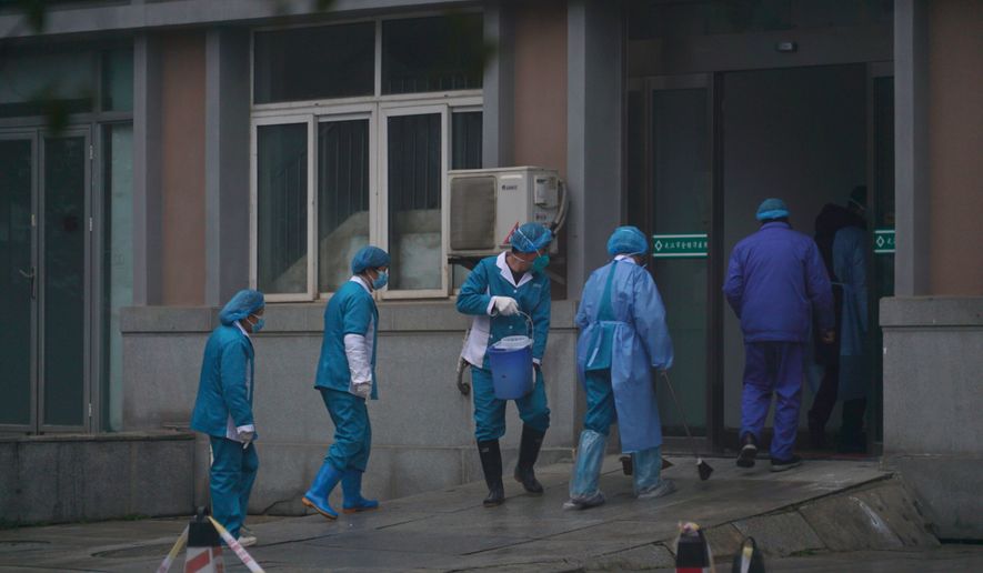Hospital staff wash the emergency entrance of Wuhan Medical Treatment Center, where some infected with a new virus are being treated, in Wuhan, China, Wednesday, Jan. 22, 2020. The number of cases of a new coronavirus from Wuhan has risen to over 400 in China health authorities said Wednesday. (AP Photo/Dake Kang)