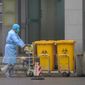 Staff move bio-waste containers past the entrance of the Wuhan Medical Treatment Center, where some infected with a new virus are being treated, in Wuhan, China, Wednesday, Jan. 22, 2020. The number of cases of a new coronavirus from Wuhan has risen over 400 in China Chinese health authorities said Wednesday. (AP Photo/Dake Kang)