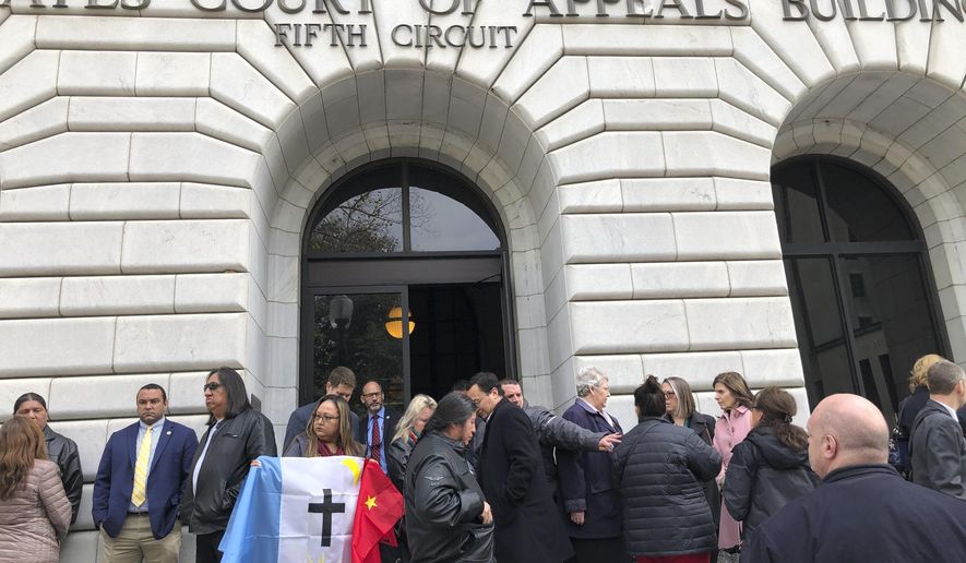 Rosa Soto Alvarez, of Tucson,, holds a flag of the Pascua Yaqui Tribe as she and other Native Americans stand outside the federal appeals court in New Orleans, Wednesday, Jan. 22, 2020. The 5th U.S. Circuit Court of Appeals was hearing arguments on the constitutionality of the Indian Child Welfare Act, which gives Native American families preference in adoption proceedings involving Native American children. Alvarez is a supporter of the law. (AP Photo/Kevin McGill)