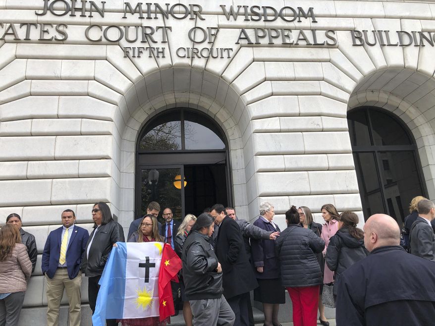 Rosa Soto Alvarez, of Tucson,, holds a flag of the Pascua Yaqui Tribe as she and other Native Americans stand outside the federal appeals court in New Orleans, Wednesday, Jan. 22, 2020. The 5th U.S. Circuit Court of Appeals was hearing arguments on the constitutionality of the Indian Child Welfare Act, which gives Native American families preference in adoption proceedings involving Native American children. Alvarez is a supporter of the law. (AP Photo/Kevin McGill)