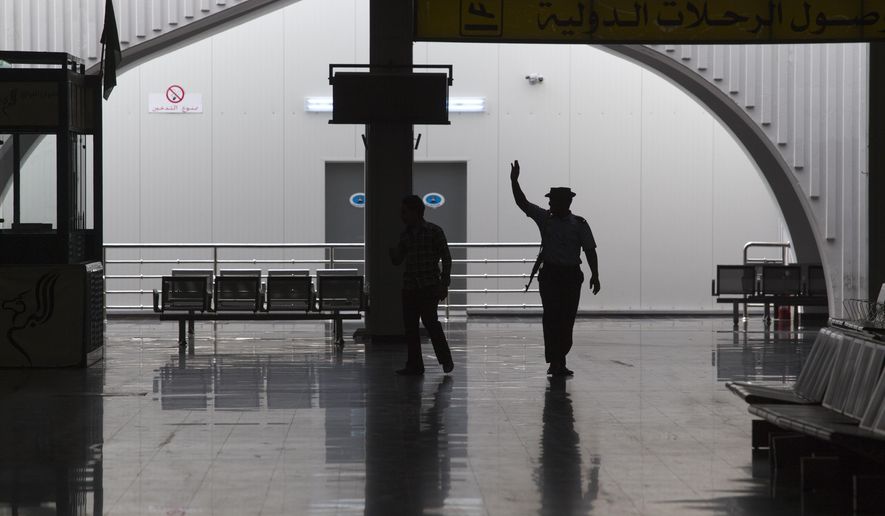 FILE - In this Aug. 20, 2011, file, photo taken on a government-organized tour, a guard waves to fellow officers in the main lobby of the international airport in Tripoli, Libya. The only functioning airport in Libya&#x27;s capital suspended its operations after coming under attack Wednesday, Jan. 22, 2020, airport authorities said, despite a tenuous truce that world powers have pushed warring parties to respect. Authorities at Mitiga airport said six Grad missiles crashed into the tarmac. (AP Photo/Dario Lopez-Mills, File)