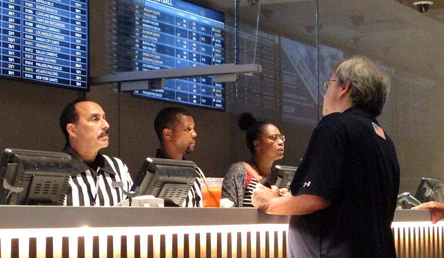 In this Sept. 5, 2019 photo, a gambler places sports bets at Bally&#x27;s casino in Atlantic City, N.J. New Jersey gambling regulators have approved wagering on the XFL, becoming the sixth state to approve bets on the revived football league that last operated in 2001. Its season begins Feb. 8, 2020. (AP Photo/Wayne Parry)