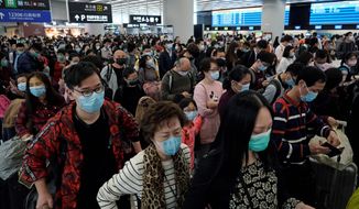 Passengers wear protective face masks at the departure hall of the high speed train station in Hong Kong on Thursday. China closed off a city of more than 11 million people Thursday, halting transportation and warning against public gatherings. (ASSOCIATED PRESS)