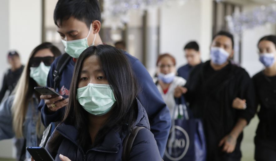 Passengers wear masks as they arrive at Manila&#39;s international airport, Philippines, Thursday, Jan. 23, 2020. The government is closely monitoring arrival of passengers as a new coronavirus outbreak in Wuhan, China has infected hundreds and caused deaths in that area. (AP Photo/Aaron Favila)