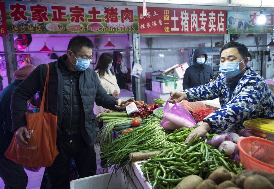 In this photo released by China&#39;s Xinhua News Agency, people shop for vegetables at a market in Wuhan in central China&#39;s Hubei Province, early Thursday, Jan. 23, 2020. China closed off a city of more than 11 million people Thursday in an unprecedented effort to try to contain a deadly new viral illness that has sickened hundreds and spread to other cities and countries in the Lunar New Year travel rush. (Xiao Yijiu/Xinhua via AP)