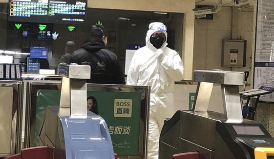 A security officer wears a hazardous materials suit at a subway station in Beijing, Friday, Jan. 24, 2020. China moved to lock down at least three cities with a combined population of more than 18 million in an unprecedented effort to contain the deadly new virus that has sickened hundreds of people and spread to other parts of the world during the busy Lunar New Year holiday. (AP Photo/Yanan Wang)