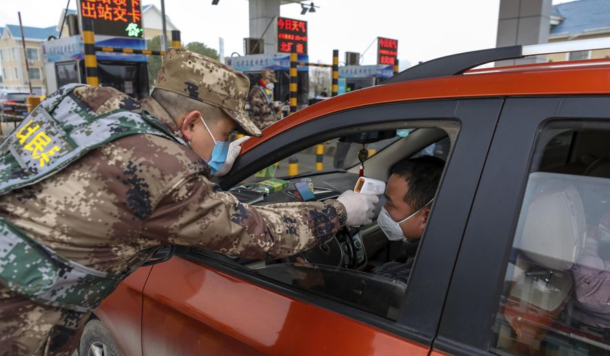 A militia member uses a digital thermometer to take a driver&#39;s temperature at a checkpoint at a highway toll gate in Wuhan in central China&#39;s Hubei Province, Thursday, Jan. 23, 2020. China closed off a city of more than 11 million people Thursday in an unprecedented effort to try to contain a deadly new viral illness that has sickened hundreds and spread to other cities and countries amid the Lunar New Year travel rush. (Chinatopix via AP)