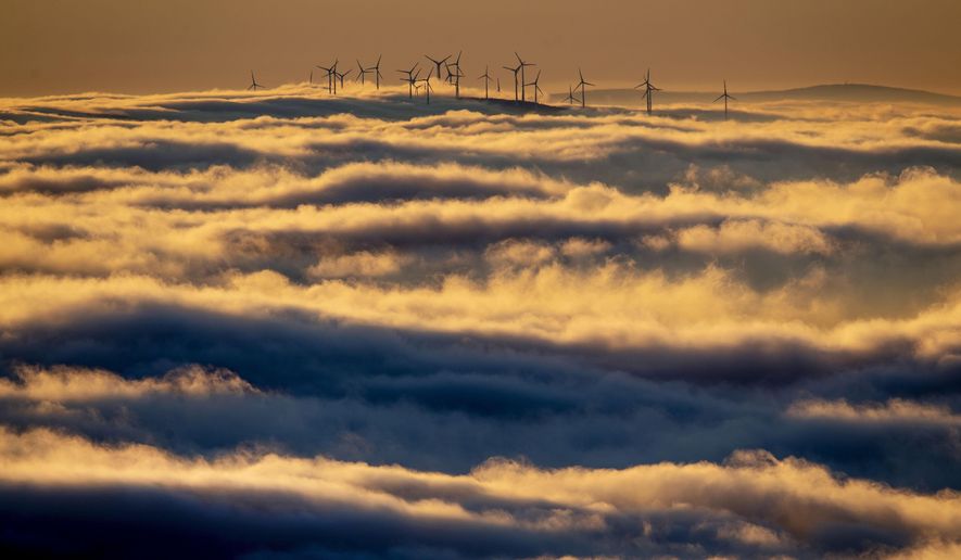 FILE - In this Jan. 6, 2020, file photo wind turbines stand on a hill and are surrounded by fog and clouds in the Taunus region near Frankfurt, Germany. Environmentally conscious investing received a lot of attention last week after the world’s largest asset manager said it plans to put climate change and sustainability at the center of its investment approach. (AP Photo/Michael Probst, File)