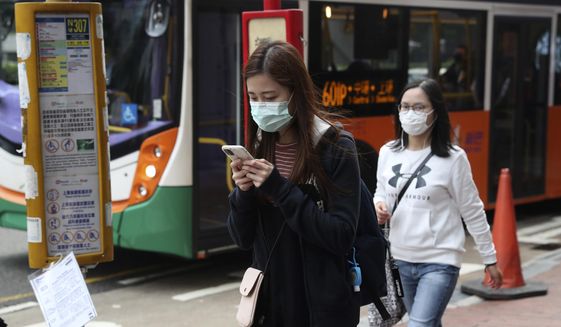 People wear protective face masks on a street in Hong Kong, Friday, Jan 24, 2020. China closed off a city of more than 11 million people Thursday, halting transportation and warning against public gatherings, to try to stop the spread of a deadly new virus that has sickened hundreds and spread to other cities and countries in the Lunar New Year travel rush. (AP Photo/Achmad Ibrahim)