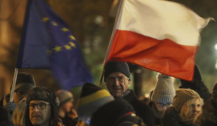 People holding a Poland and European Union flags take part in a protest outside Poland&#x27;s parliament building as lawmakers voted to approve the much-criticized legislation that allows politicians to fire judges who criticize their decisions, in Warsaw, Poland, Thursday, Jan. 23, 2020. Poland&#x27;s lawmakers gave their final approval Thursday to legislation that will allow politicians to fire judges who criticize their decisions, a change that European legal experts warn will undermine judicial independence. (AP Photo/Czarek Sokolowski)
