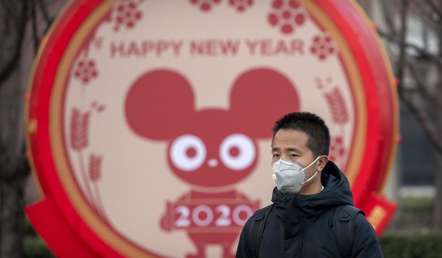 FILE - In this Jan. 22, 2020 photo, a man wears a face mask as he walks past a display for the upcoming Lunar New Year, the Year of the Rat, in Beijing, Wednesday, Jan. 22, 2020. A virus that has killed more than two dozen people and sickened hundreds more has all but shut down China&#39;s biggest holiday of the year, the Lunar New Year. Instead of family reunions or sightseeing trips, many of the country&#39;s 1.4-billion people are hunkering down as the country scrambles to prevent the illness from spreading further. (AP Photo/Mark Schiefelbein, File)