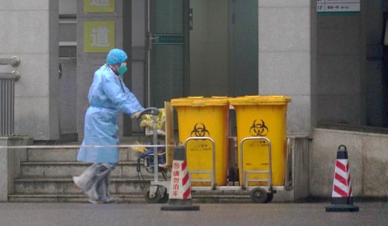 In this Wednesday, Jan. 22, 2020, file photo, a staff member moves bio-waste containers past the entrance of the Wuhan Medical Treatment Center in Wuhan, China, where some people infected with a new virus are being treated. The new virus comes from a large family of coronaviruses, some causing nothing worse than a cold. Others named SARS and MERS have killed hundreds in separate outbreaks. (AP Photo/Dake Kang, File) **FILE**