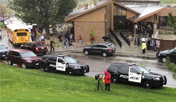 FILE - In this May 7, 2019, file photo, police and others are seen outside a recreation center where students are reunited with their parents after a shooting at STEM School Highlands Ranch, in the Denver suburb of Highlands Ranch, Colo. The security guard who accidentally injured two students while shooting at a deputy whom he thought was a shooter will not be criminally charged, but he must complete community service and attend a diversion program for improper use of a weapon on school grounds, a special prosecutor said Friday, Jan. 24, 2020. (AP Photo/David Zalubowski, File)