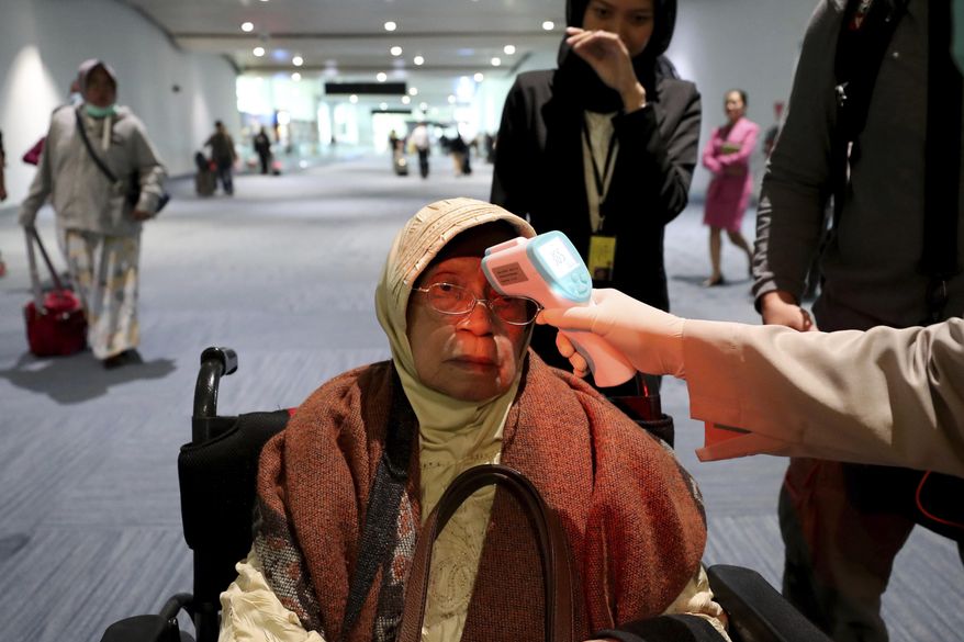 In this Wednesday, Jan. 22, 2020, file photo, a health official scans the body temperature of a passenger as she arrives at the Soekarno-Hatta International Airport in Tangerang, Indonesia. Indonesia is screening travelers from overseas for a new type of coronavirus as fears spread about a mysterious infectious disease after its first death reported in China. (AP Photo/Tatan Syuflana, File)