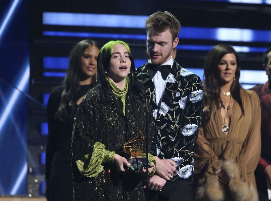 Billie Eilish, left, and Finneas O&#39;Connell accept the award for song of the year for &quot;Bad Guy&quot; at the 62nd annual Grammy Awards on Sunday, Jan. 26, 2020, in Los Angeles. At right looking on is presenter Karen Fairchild. (Photo by Matt Sayles/Invision/AP)