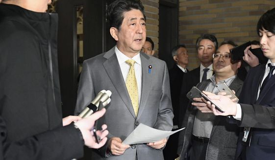 Japanese Prime Minister Shinzo Abe, center, speaks to reporters at his official residence in Tokyo Sunday, Jan. 26, 2020. Abe said he is making arrangements to fly Japanese people home from the Chinese city of Wuhan, hit by an outbreak of a new virus recently. (Mizuki Ikari/Kyodo News via AP)