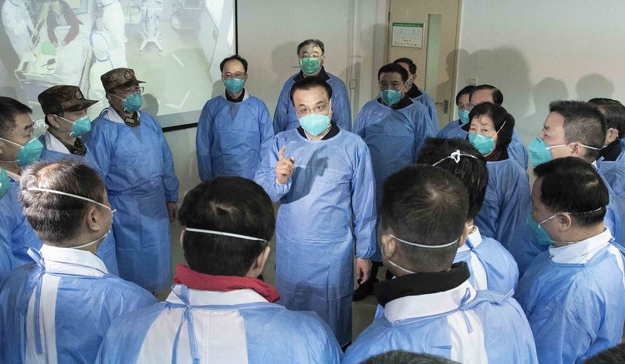 In this photo released by China's Xinhua News Agency, Chinese Premier Li Keqiang, center, speaks with medical workers at Wuhan Jinyintan Hospital in Wuhan in central China's Hubei province, Monday, Jan. 27, 2020. China on Monday expanded its sweeping efforts to contain a deadly virus, extending the Lunar New Year holiday to keep the public at home and avoid spreading infection. (Li Tao/Xinhua via AP)