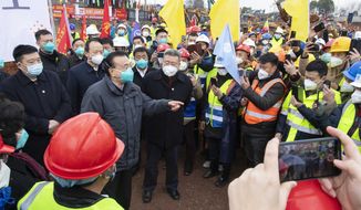 In this photo released by China&#39;s Xinhua News Agency, Chinese Premier Li Keqiang, fourth left, speaks with construction workers at the site of makeshit field hospital being built in Wuhan in central China&#39;s Hubei province, Monday, Jan. 27, 2020. China on Monday expanded its sweeping efforts to contain a deadly virus, extending the Lunar New Year holiday to keep the public at home and avoid spreading infection. (Li Tao/Xinhua via AP)