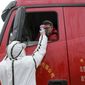 A worker in a hazardous materials suit takes the temperature of a truck driver at a checkpoint in Huaibei in central China&#39;s Anhui Province, Monday, Jan. 27, 2020. China on Monday expanded sweeping efforts to contain a viral disease by extending the Lunar New Year holiday to keep the public at home and avoid spreading infection as the death toll rose to 80. (Chinatopix via AP)