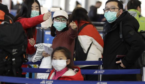 Passengers wearing masks wait in a line to check-in to a flight to Shanghai at the Vaclav Havel International Airport in Prague, Czech Republic, Monday, Jan. 27, 2020. Prague&#39;s international airport is launching an information campaign for travellers who develop symptoms possibly linked to a new coronavirus illness. (AP Photo/Petr David Josek)
