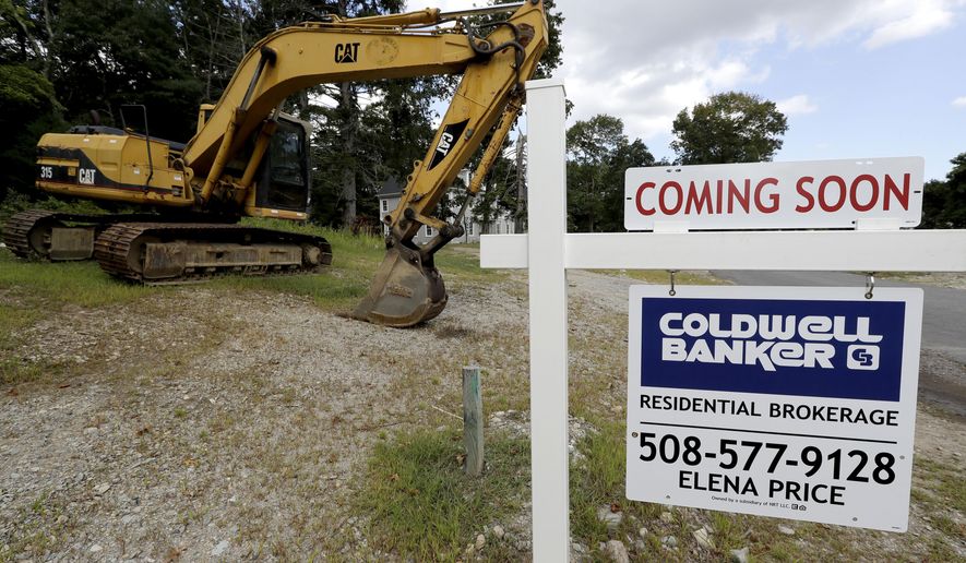 FILE - In this Sept. 3, 2019, file photo a sign rests near a piece of earth-moving equipment, left, on a plot of land, in Westwood, Mass. On Monday, Jan. 27, 2020, the Commerce Department reports on sales of new homes in December. (AP Photo/Steven Senne, File)