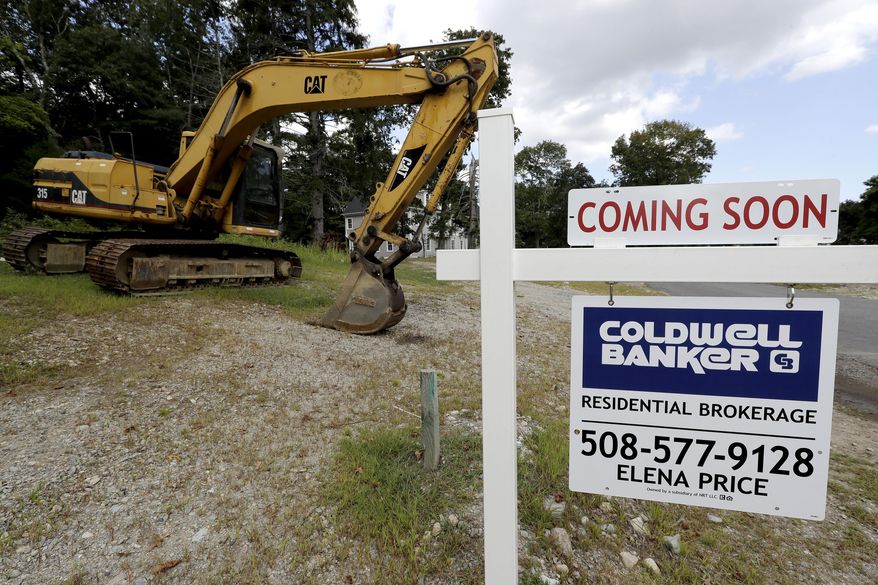 FILE - In this Sept. 3, 2019, file photo a sign rests near a piece of earth-moving equipment, left, on a plot of land, in Westwood, Mass. On Monday, Jan. 27, 2020, the Commerce Department reports on sales of new homes in December. (AP Photo/Steven Senne, File)