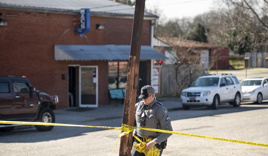 A law enforcement officer removes crime scene tape in front of Mac's Lounge, the scene of an early morning bar shooting, Sunday, Jan. 26, 2020, in Hartsville, S.C. (AP Photo/Sean Rayford)