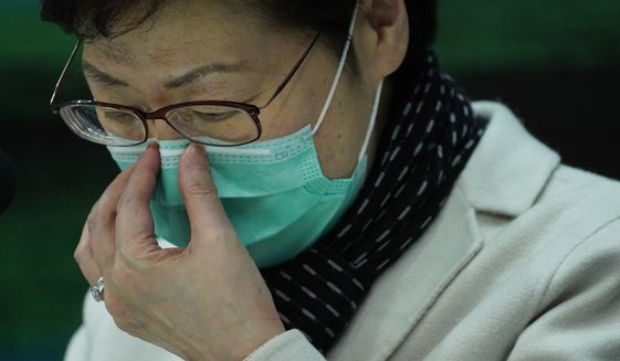 Hong Kong Chief Executive Carrie Lam adjusts protective face mask during a press conference held in Hong Kong, Tuesday, Jan. 28, 2020. Lam has announced that all rail links to mainland China will be cut starting Friday as fears grow about the spread of a new virus. (AP Photo/Vincent Yu)