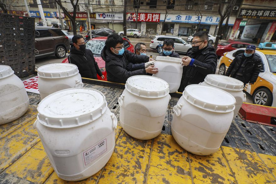 Workers unload canisters of disinfectant from a truck in Wuhan in central China's Hubei Province, Tuesday, Jan. 28, 2020. Hong Kong's leader announced Tuesday that all rail links to mainland China will be cut starting Friday as fears grow about the spread of a new virus. (Chinatopix via AP)