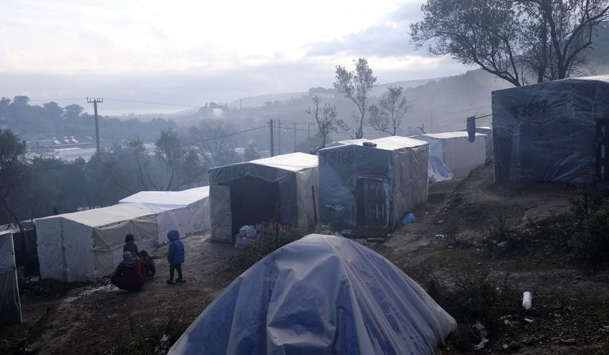 Migrants stand outside their makeshift tents outside the perimeter of the overcrowded Moria refugee camp after a rainfall on the northeastern Aegean island of Lesbos, Greece, Tuesday, Jan. 28, 2020. Greece has been the first point of entry into the European Union for hundreds of thousands of people fleeing war or poverty at home, with most arriving on eastern Aegean islands from nearby Turkey. (AP Photo/Aggelos Barai)