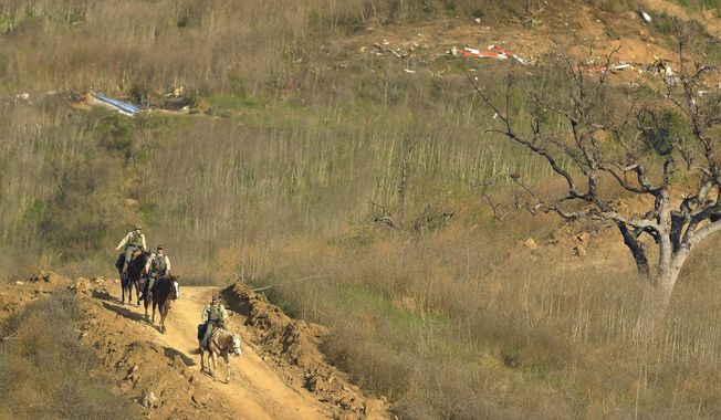 Sheriff's deputies on horseback leave the scene of a helicopter crash, Monday, Jan. 27, 2020, that killed former NBA basketball player Kobe Bryant, his 13-year-old daughter, Gianna, and seven others, in Calabasas, Calif., on Sunday. (AP Photo/Mark J. Terrill)