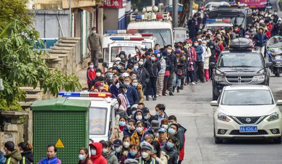People line up to buy face masks from a medical supply company in Nanning in southern China&#39;s Guangxi Zhuang Autonomous Region, Wednesday, Jan. 29, 2020. Countries began evacuating their citizens Wednesday from the Chinese city hardest-hit by a new virus that has now infected more people in China than were sickened in the country by SARS. (Chinatopix via AP)