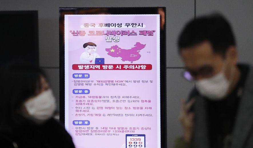 FILE - In this Monday, Jan. 27, 2020, file photo, a poster warning about coronavirus is seen as passengers wear masks in a departure lobby at Incheon International Airport in Incheon, South Korea. British Airways and Asian budget carriers Lion Air and Seoul Air are suspending all flights to China as fears spread about the outbreak of a new virus that has killed more than 130 people. British Airways said Wednesday it is immediately suspending all flights to and from mainland China after the U.K. government warned against unnecessary travel to the country. (AP Photo/Ahn Young-joon, File)