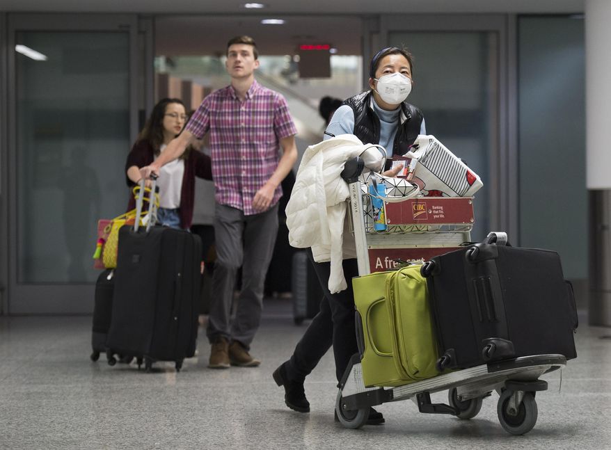 A woman wears a mask following the outbreak of a new virus as people arrive from the International terminal at Toronto Pearson International Airport in Toronto on Saturday, Jan. 25, 2020. A Toronto hospital said Saturday it has a confirmed case of the deadly virus from China, Canada's first. Sunnybrook Health Sciences Centre said it is "caring for a patient who has a confirmed case of the novel coronavirus that originated in Wuhan, China." (Nathan Denette/The Canadian Press via AP)