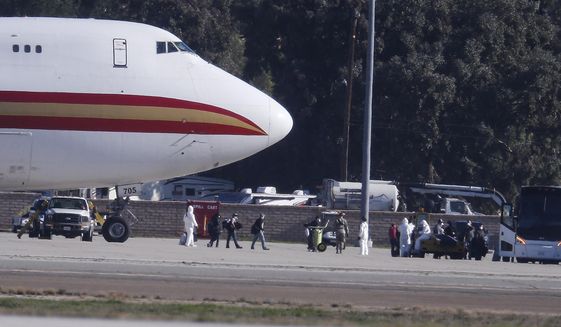 Passengers board buses after arriving on an airplane carrying U.S. citizens being evacuated from Wuhan, China, at March Air Reserve Base in Riverside, Calif. Jan. 29, 2020.   The passengers will undergo additional screenings in California and be placed in temporary housing. Officials have not said how long they will stay there.  (AP Photo/Ringo H.W. Chiu)