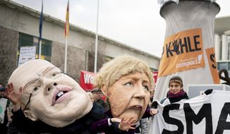 Activists depicting German Chancellor Angela Merkel, right, and German Economy Minister Peter Altmaier are protesting in front of the Federal Chancellery against the coal phase-out law and the resulting delayed coal phase-out in Berlin, Germany, Wednesday, Jan.29, 2020. (Kay Nietfeld/dpa via AP)