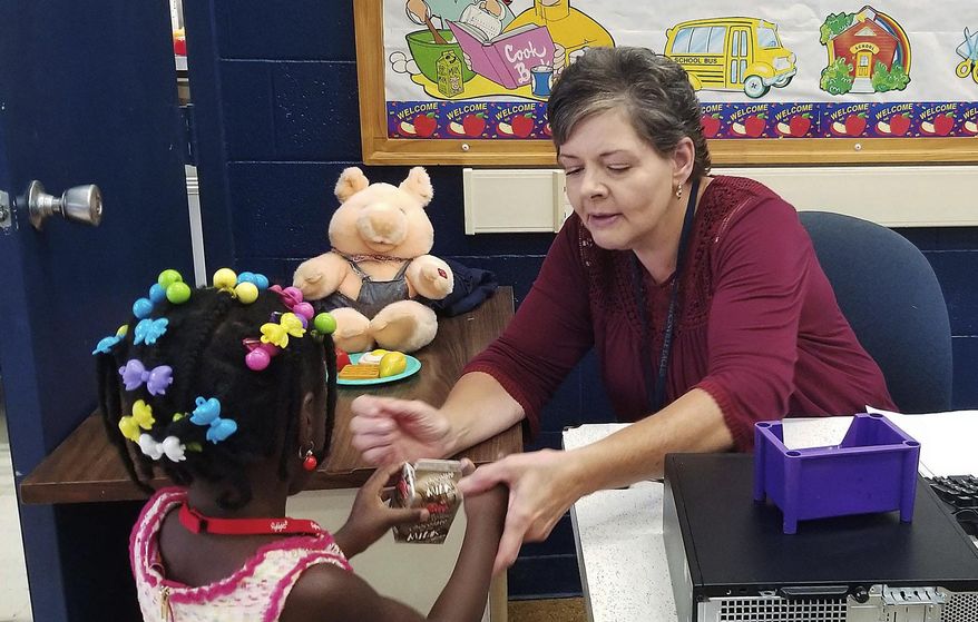 FILE - In this Aug. 20, 2019, file photo, Secretary Judy Stewart helps a Hedgesville Elementary School student get breakfast on the first day of classes in Hedgesville, W.Va. On Jan. 29, 2020, the West Virginia House of Delegates rejected a bill that would have pushed back the start of the public school year to no earlier than Sept. 1. Proponents of the bill said many schools don't have the proper ventilation and air conditioning during the hot days of August. (Jenni Vincent/The Herald-Mail via AP, File)