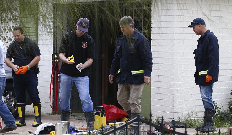 Phoenix Fire Department investigators look through evidence at a home where skeletal remains were found Wednesday, Jan. 29, 2020, in Phoenix. The remains have been found at a house where authorities previously removed at least one child as part of a child abuse investigation in which both parents of that child were in custody, police said Wednesday. (AP Photo/Ross D. Franklin)