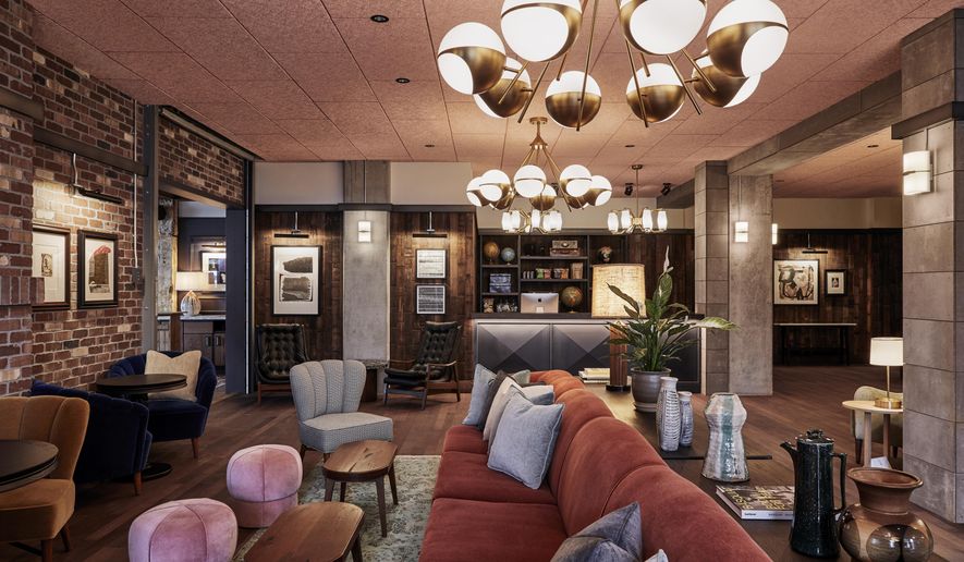 This photo shows the lobby in The Hoxton Hotel in Portland, Ore. London/L.A.-based Fettle designed Portland's Hoxton. Alongside newly-built rooms, public areas were situated in an old converted movie theater. Tailored but comfy mohair and leather seating and warm wood side tables blend with distressed rugs and displays of ceramics, plants and books. Refurbished timber and concrete beams frame the spaces. And there's a great story about the reception area's wood paneling. "We used a lot of local suppliers and material for this project," Parker says. "The area around Portland is a big producer of Maraschino cherries; the visible face of the wall is made from the outside of reclaimed cherry vats. If you look closely you can even see the imprints where the metal belts that hold the huge vats together were pressed against the wood." (Ennismore/The Hoxton via AP)