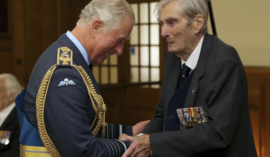 FILE - In this Sept. 17, 2017 file photo, Britain's Prince Charles, left, shakes hands with Battle of Britain veteran Wing Commander Paul Farnes, in Dover, England. One of the last remaining and most decorated Battle of Britain fighter pilots who helped protect Britain during World War II has died. The Battle of Britain Memorial Trust said Wing Commander Paul Farnes died at his home Tuesday, Jan. 28, 2020 at the age of 101. (Gareth Fuller/PA via AP, File)