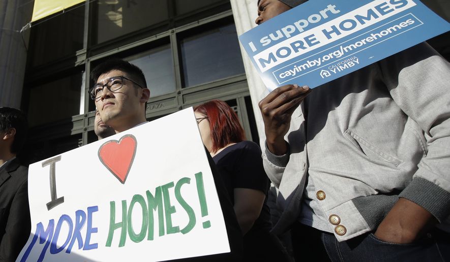 FILE - In this Jan. 7, 2020, file photo, men hold up signs at a rally outside of City Hall in Oakland, Calif., in support of more housing. California lawmakers have failed to pass the most ambitious proposal yet to combat a growing housing crisis in the nation's most populous state, voting down legislation Wednesday, Jan. 29, that would have overridden local zoning laws to let developers to build small apartment buildings in neighborhoods reserved for single-family homes. (AP Photo/Jeff Chiu, File)