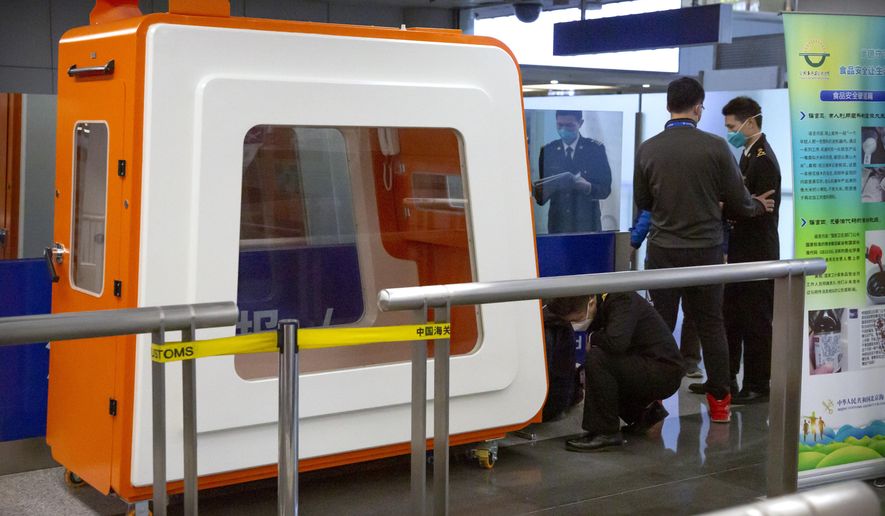Officials in face masks work near a mobile isolation unit at Beijing Capital International Airport in Beijing, Thursday, Jan. 30, 2020. China counted 170 deaths from a new virus Thursday and more countries reported infections, including some spread locally, as foreign evacuees from China's worst-hit region returned home to medical observation and even isolation. (AP Photo/Mark Schiefelbein)