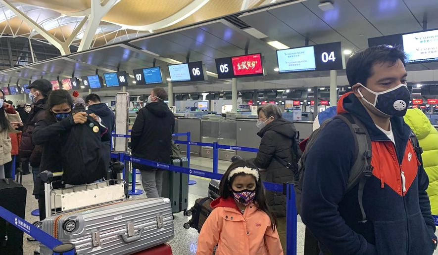 Travelers wearing face masks stand in line at the check-in counters for Cathay Pacific at Shanghai Pudong International Airport in Shanghai, Thursday, Jan. 30, 2020. China counted 170 deaths from a new virus Thursday and more countries reported infections, including some spread locally, as foreign evacuees from China's worst-hit region returned home to medical observation and even isolation. (AP Photo/Erika Kinetz)