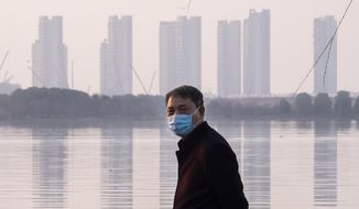 A man wears a face mask as he stands along the waterfront in Wuhan in central China&#39;s Hubei Province, Thursday, Jan. 30, 2020. China counted 170 deaths from a new virus Thursday and more countries reported infections, including some spread locally, as foreign evacuees from China&#39;s worst-hit region returned home to medical observation and even isolation. (AP Photo/Arek Rataj)